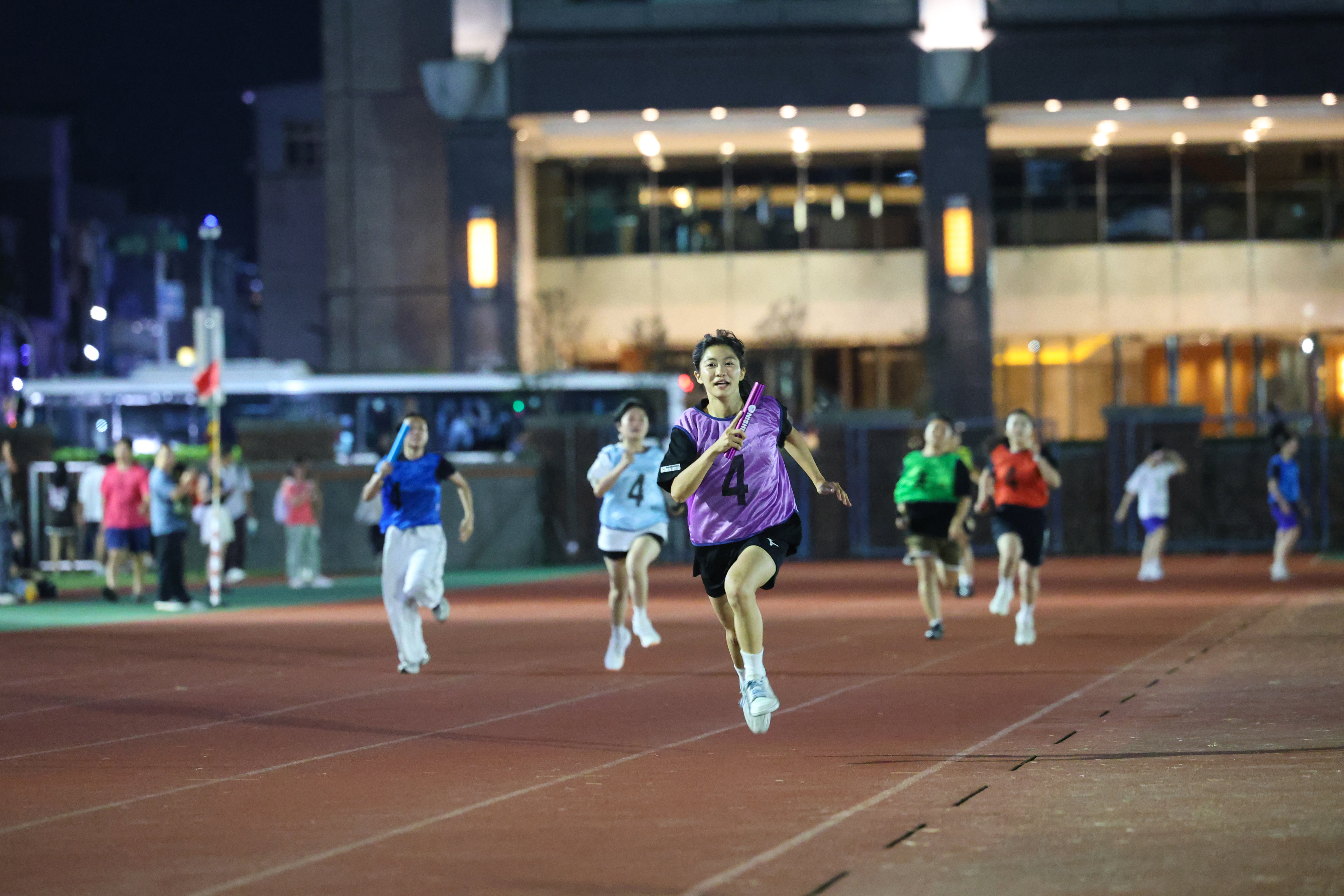 Runners sprint at full speed on the track, striving to achieve the best possible results for their teams