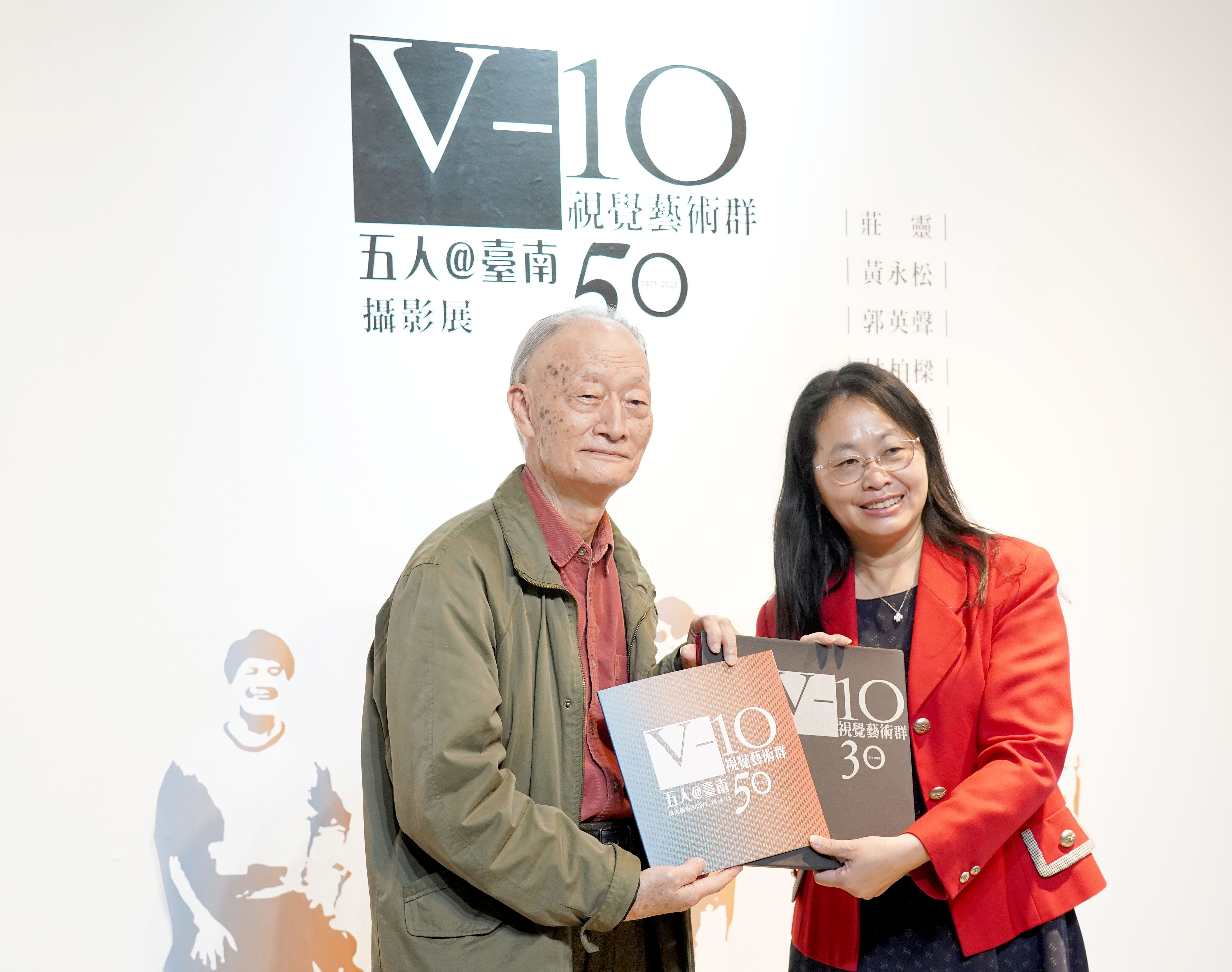 「V-10 視覺藝術群」會長莊靈（左）致贈展覽畫冊給臺灣藝術史料中心暨成大藝術所所長吳奕芳