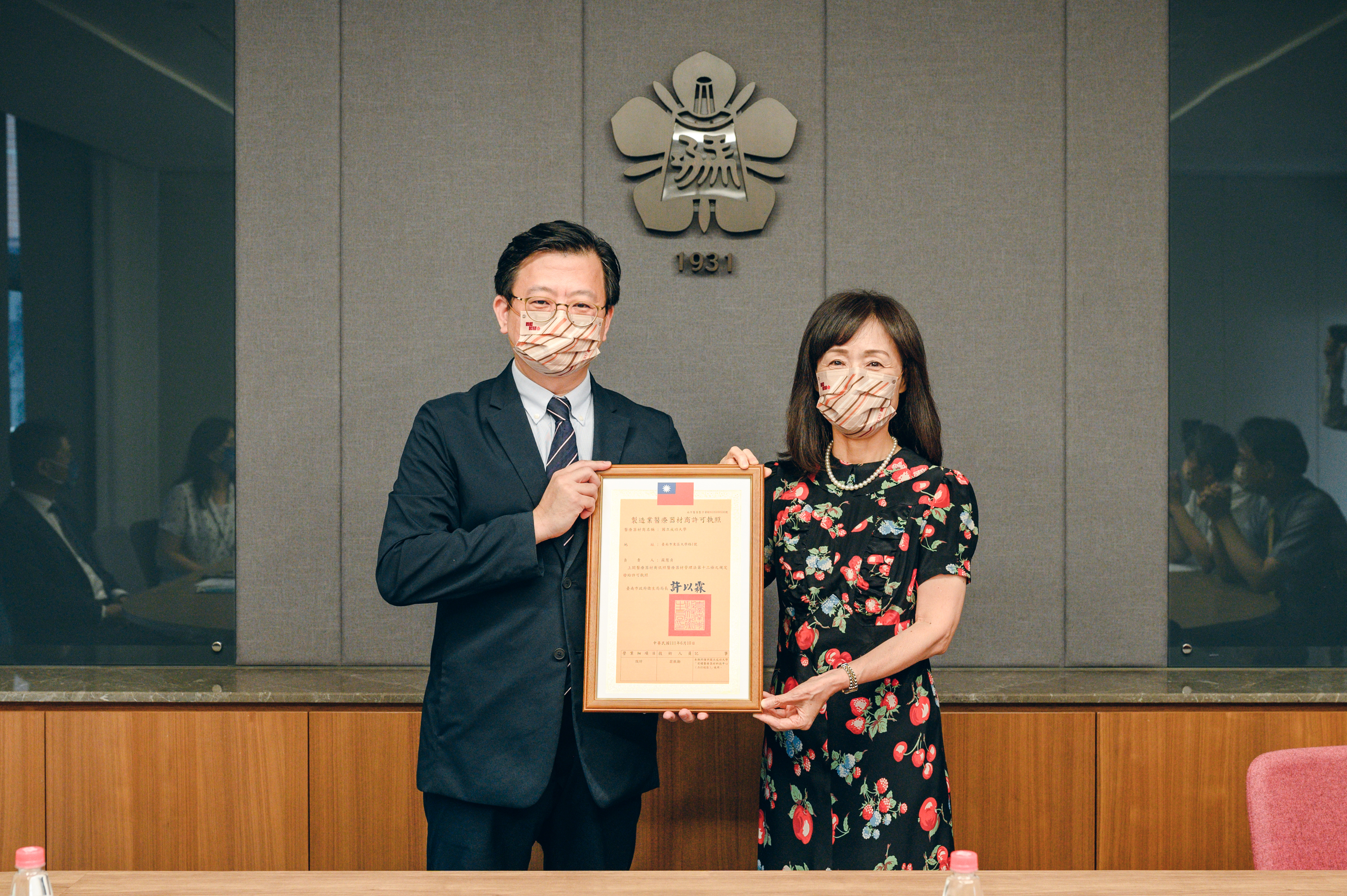 台南市衛生局長（左）許以霖頒贈許可證，由成大校長蘇慧貞（右）代表接受